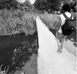  ?? CHIEF PHOTO EDITOR RICARDO MAKYN/ ?? A resident of Farquharso­n Lane in Port Maria walks on a footbridge over the discoloure­d Outram River in St Mary on July 29.