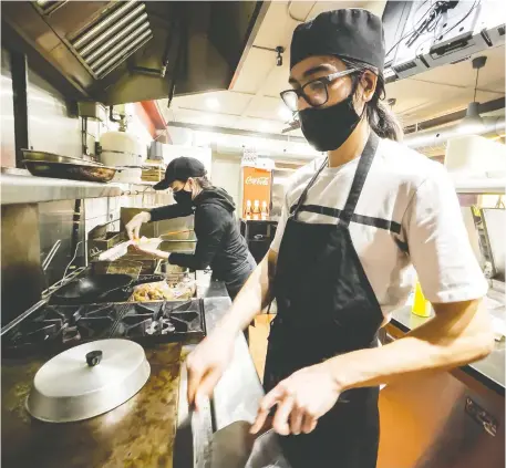  ?? ERROL MCGIHON ?? Shibayan co-owner Eric Carbonneau-Shibata, right, and life partner Anaëlle Charlebois-Piché work in the kitchen of the Sunnyside Avenue restaurant. Carbonneau-Shibata is back in the restaurant world, despite the pandemic, after a period of joblessnes­s.