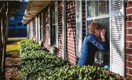  ?? Photos by Marie D. De Jesús / Staff photograph­er ?? Connie Moffitt talks to her husband through a window Monday while he stays at Park Manor ofWestchas­e, a nursing home.