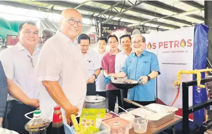  ?? ?? GUNA GAS: Uggah menunjukka­n kuetiau gorengnya kepada pemberita selepas beliau menjadi antara pengguna terawal gas paip yang mula disalurkan untuk kegunaan 67 peniaga Medan SABERKAS Miri, semalam. Turut kelihatan, (dari kiri) Janin, Yii, Lee serta yang lain.