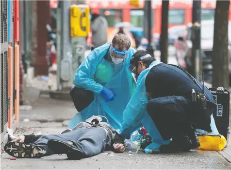  ?? JASON PAYNE/POSTMEDIA ?? Ambulance paramedics help a man suffering a drug overdose on Columbia Street. After being injected with Naloxone by the paramedics the man came to, got up and walked away.