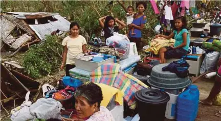  ?? [FOTO AFP] ?? Mangsa Taufan Haima mengumpul barangan yang boleh dipakai selepas kediaman mereka musnah di badai taufan di Cayagan, utara Filipina, semalam.