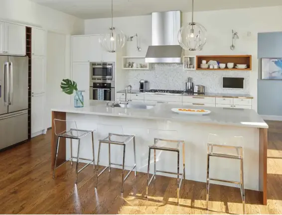  ??  ?? Above A recent kitchen renovation took the cabinets from grey to glossy white and saw a pair of office task lights hard-wired into the wall over the stove. Pendant lights are from West Elm, while the low-backed Lucite stools are from CB2