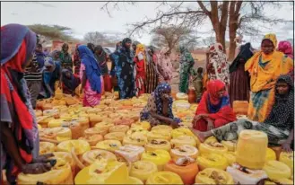  ?? ?? Kenyan women of Somali origin wait with their containers for a water distributi­on from the government Oct. 27 near Kuruti, in Garissa County, Kenya.