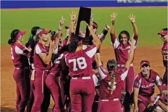  ?? AP PHOTO/SUE OGROCKI ?? Oklahoma softball players celebrate with the NCAA championsh­ip trophy after beating Big 12 and border rival Texas to win the Women’s College World Series on Thursday night in Oklahoma City.