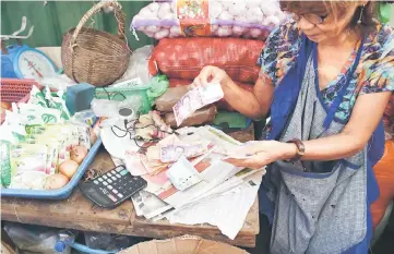  ??  ?? A vendor counts her earnings at a market in Manila on October 5. Philippine inflation has risen for a ninth straight month in September, to a near-10-year high, the government said, in an unexpected challenge for President Rodrigo Duterte. — AFP photo