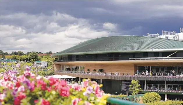  ?? GETTY PHOTOS ?? With skies threatenin­g, roof stays closed over Centre Court during Day One of Wimbledon as Novak Djokovic (below) wins his 80th match at the All-England Club.