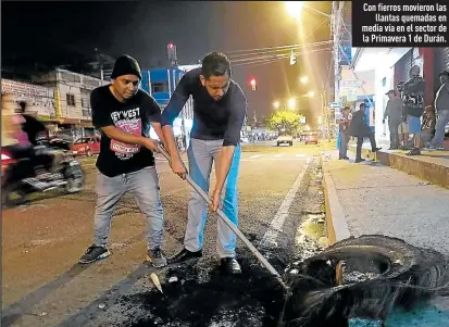  ?? Fotos: Marcelo Gutiérrez / EXTRA’ ?? Con fierros movieron las
llantas quemadas en media vía en el sector de la Primavera 1 de Durán.