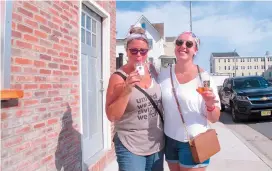  ??  ?? Eileen Kasunich (left) and Kelsey Tierney drink cocktails on the sidewalk outside a beer hall in Atlantic City. — Ti Gong