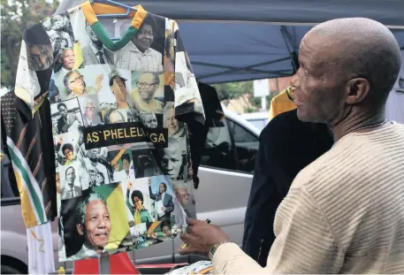  ?? BONGANI MBATHA African News Agency (ANA) ?? A SHOPPER browses through items at one of the many roadside stalls selling ANC parapherna­lia in Durban’s CBD, as the party’s leadership holds meetings in the city and visits areas in KwaZulu-Natal. |