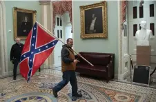  ?? ?? A supporter of US President Donald Trump carries a Confederat­e flag as he protests in the US Capitol, in Washington, DC.