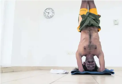  ?? Photos Antonie Robertson / The National. ?? Ivan Stanley, a yoga practition­er and instructor for more than 15 years, attempts the world’s longest headstand. No previous official record had been set. Mr Stanley set a time of 61 minutes.