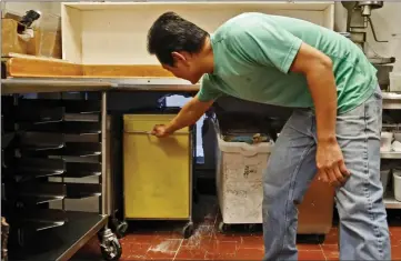  ?? Katharine Lotze/The Signal ?? (Above) Thuong Sauv moves equipment away to reveal a hole that a thief cut into a wall to break into his donut shop in Stevenson Ranch on Monday.