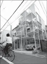  ?? AP/SHIZUO KAMBAYASHI ?? Architect Sou Fujimoto’s assistant Masaki Iwata stands inside Fujimoto’s house of glass in Tokyo, which sits in a residentia­l area in Tokyo.