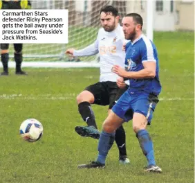  ??  ?? Carmarthen Stars defender Ricky Pearson gets the ball away under pressure from Seaside’s Jack Watkins.