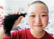  ??  ?? Lim showing a lock of her hair after getting her head shaved at the charity event yesterday.