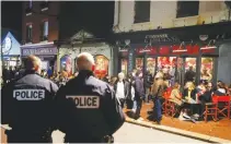  ?? REUTERS ?? POLICEMEN stand guard while people enjoy dinner and drinks before the French Prime Minister Edouard Philippe’s announceme­nt of the shutdown of nonessenti­al commerce and places takes effect in France at midnight, in Le Touquet, France, March 14.