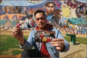  ?? AP/REED SAXON ?? Jeff DeGuia, 28, whose grandfathe­r emigrated from the Philippine­s, holds up family pictures at Unidad (Unity) Park in Los Angeles.