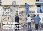  ??  ?? PREPARATIO­N Workers board up windows in Miami