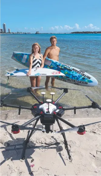  ?? Picture: GLENN HAMPSON ?? Champion surfer Nikki Van Dijk and Ironman TJ Hendy take part in a 5G drone demonstrat­ion at Labrador yesterday.