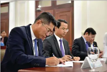  ?? AFP ?? Nguyen Thanh Nam (left), director general of Sabeco, signs documents as he attends the auction of the brewer’s shares at the Ho Chi Minh City stock exchange in December last year. Thai brewer ThaiBev has invested $4.8 billion in the company’s Saigon Beer.