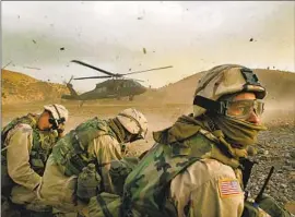  ?? Rick Loomis Los Angeles Times ?? MEMBERS OF THE 82nd Airborne duck as a helicopter prepares to withdraw troops in Afghanista­n. The war drew comparativ­ely less attention in U.S. culture.