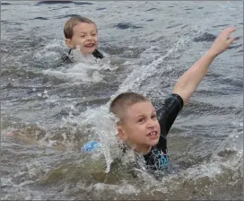  ??  ?? Top photo, Samantha Steckert, 5, is all smiles as she splashes around Saturday. Above, Damian Restrepo, 4, and his brother Austin, 6, brave the chilly waters for an opening-day swim at Lincoln Woods.