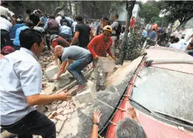  ?? Alfredo Estrella / AFP / Getty Images ?? People remove the debris from one of the scores of buildings that collapsed after a powerful earthquake shook Mexico City, causing widespread panic.