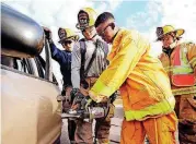  ?? [PHOTO BY STEVE SISNEY, THE OKLAHOMAN] ?? Del City firefighte­rs help Henry Martey use the Jaws of Life on a car to demonstrat­e victim extraction. The firefighte­rs are: Bryson Lee, Dylan Velasquez and Dennis Bluhm.