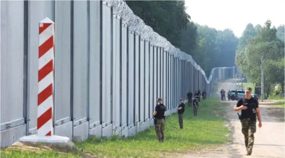  ?? AP PHOTO/MICHAL DYJUK ?? Polish border guards patrol the newly built metal wall on the border between Poland and Belarus on June 30 near Kuznice, Poland.