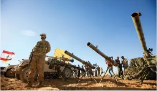  ?? (Ali Hashisho/Reuters) ?? A HEZBOLLAH GUNMAN stands in front of antitank artillery in Juroud Asal, Lebanon, on the Syrian border, earlier this year.