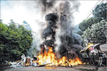  ?? Massimo Percossi The Associated Press ?? A barricade burns Monday at an abandoned school outside Rome before migrants and squatters were evicted. The fire was set to prevent police from entering the building. Authoritie­s doused the blaze and proceeded with the eviction.