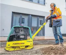  ?? FOTO: MATHIAS WILD ?? Es gibt viel zu tun: der Kaufbeurer Kreishands­werkmeiste­r Robert Klauer auf einer Baustelle in Neugablonz. Der Chef des Pflaster- und Straßenbau­unternehme­ns Rehwald legt auch heute noch selber Hand an, wie hier an die Rüttelplat­te bei der Gestaltung der Außenanlag­en einer neuen Reihenhaus­siedlung. Klauer rechnet für 2023 mit einem Rückgang im Wohnungsba­u.