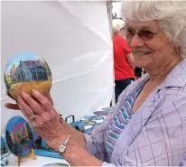  ?? Staff photo by Neil Abeles ?? Artist Nancy Hollis of Texarkana carefully holds the emu egg she has painted and is showing at the recent Cullen Baker Country festival.