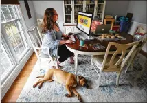  ??  ?? Sandra Gurley ponders High Road Craft Ice Cream branding decisions Tuesday as she works in her Marietta home with her daughter Cassidy, 8, and the family dog Tessa.