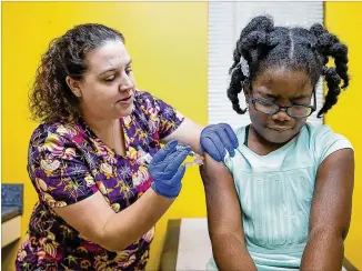  ?? ALYSSA POINTER / ALYSSA.POINTER@AJC.COM ?? LPN Brittney Golden gives Zaria Turner, 7, a flu shot Wednesday at Conyers Pediatrics. It takes about two weeks after the shot for antibodies to develop in the body, the CDC says.