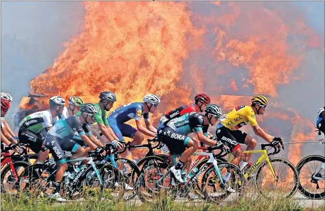  ??  ?? EL TOUR EN LLAMAS. El pelotón, con el líder Greg Van Avermaet, pasa al lado de unas balas de paja ardiendo camino del Muro de Bretaña dejando esta curiosa imagen.