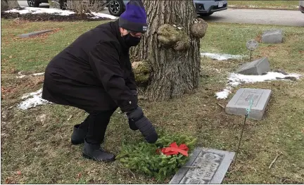  ?? BILL DEBUS — THE NEWS-HERALD ?? Betsy Hyde places a wreath at a veteran’s grave at Evergreen Cemetery in Painesvill­e on Dec. 19 during a Wreaths Across America event.