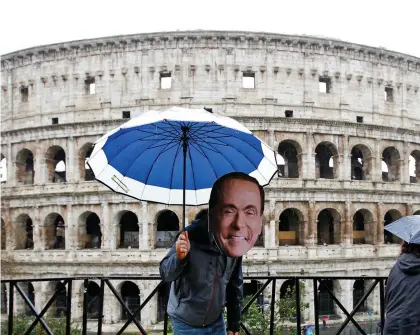  ??  ?? An activist wearing a mask of Forza Italia party leader Silvio Berlusconi poses in front of the Colosseum in Rome