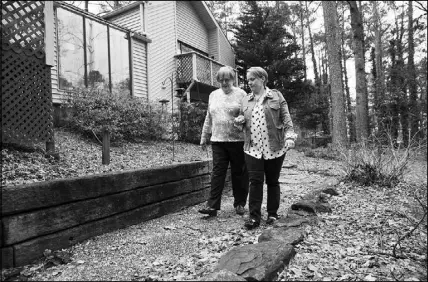  ??  ?? Mother and daughter walk outside the split-level house they share in suburban Atlanta. Betsy’s living area is on the ground f loor, where there’s a bedroom, bath and den; Susan lives upstairs.