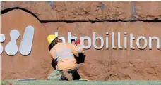  ?? — Reuters ?? A man mends a sign at the entrance to BHP Billiton’s iron ore plant in Port Hedland, Australia.