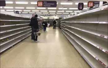  ?? IRSTY WIGGLESWOR­TH — THE ASSOCIATED PRESS ?? People stand in an aisle of empty shelves in a supermarke­t in London, amid panic-buying due to the coronaviru­s outbreak. A pandemic forcing everyone to stay home could be the perfect moment for online grocery services. In practice, they’ve been struggling to keep up with a surge in orders, highlighti­ng their limited ability to respond to an unpreceden­ted onslaught of demand. After panic buying left store shelves stripped of staples like pasta, canned goods and toilet paper, many shoppers quickly found online grocery delivery slots almost impossible to come by, too.