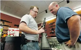  ?? ROSS D. FRANKLIN/ THE ASSOCIATED PRESS ?? Store owner Tommy Rompel, left, shows Shaun McClusky a shotgun similar to those to be given away under a program McClusky launched to provide residents in crime- prone areas with free guns.