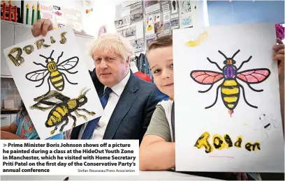  ?? Stefan Rousseau/Press Associatio­n ?? Prime Minister Boris Johnson shows off a picture he painted during a class at the HideOut Youth Zone in Manchester, which he visited with Home Secretary Priti Patel on the first day of the Conservati­ve Party’s annual conference