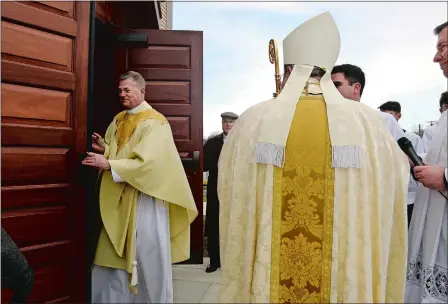  ?? PHOTOS BY DANA JENSEN/THE DAY ?? After receiving the keys from Most Reverend Bishop Michael Cote, back to camera, the Rev. Dennis Perkins, left, to whom the pastoral care of St. Michael Church is entrusted, opens the doors to the church for its Mass of Dedication on Saturday in Stonington.