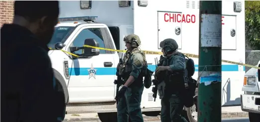  ?? PAT NABONG/SUN-TIMES ?? Members of a SWAT team walk along West Division Street near the 1200 block of North Mason Ave. in the Austin neighborho­od, where a person was fatally shot and two were injured Friday.