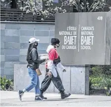  ?? NATIONAL POST ?? Pedestrian­s wearing masks walk past Canada’s National Ballet School on Jarvis Street in Toronto during the COVID-19 pandemic on Monday.