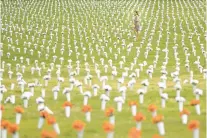  ?? NATHAN HOWARD/GETTY ?? Jordan Costa, project manager for the community violence initiative at the Giffords Law Center, walks through a field of flowers representi­ng deaths from gun violence at the Giffords Gun Violence Memorial in front of the Washington Monument in Washington, D.C.