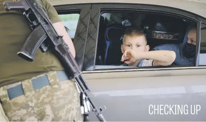  ?? Picture: EPA-EFE ?? A boy sits in a car as an Ukrainian soldier checks documents at the Novotroits­ke checkpoint between the government and pro-Russian militants-controlled territorie­s near Donetsk, Ukraine.