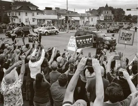  ?? Scott Olson / Getty Images ?? Supporters and protesters watch as the motorcade carrying President Donald Trump passes by Tuesday in Kenosha, Wis.